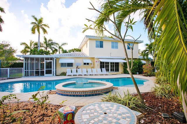 view of swimming pool featuring an in ground hot tub, a patio area, and a sunroom