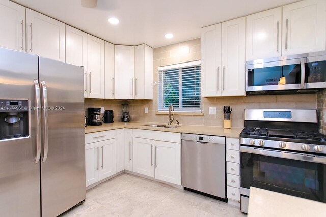 kitchen featuring stainless steel appliances, decorative backsplash, sink, and white cabinets