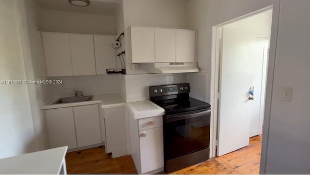 kitchen featuring tasteful backsplash, sink, white cabinets, light hardwood / wood-style floors, and black electric range oven