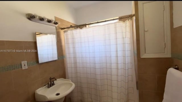 bathroom with sink, tile walls, and a shower with shower curtain