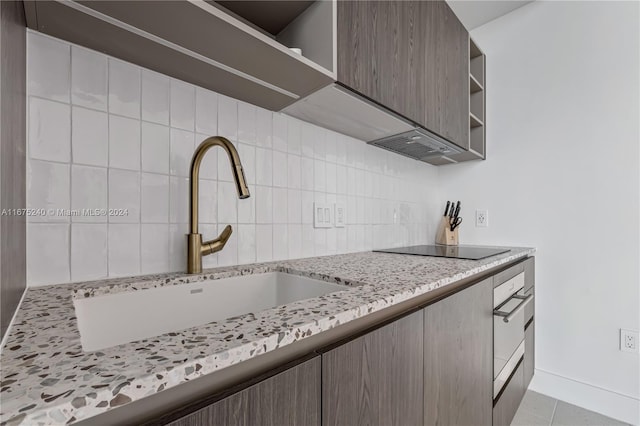 kitchen with light stone counters, light tile patterned floors, sink, oven, and black electric stovetop