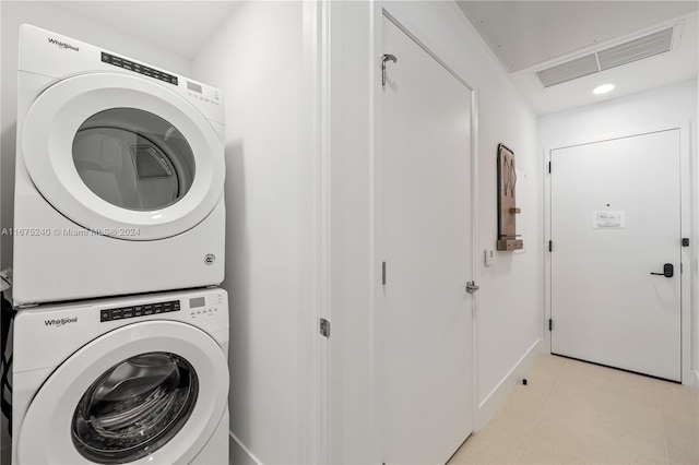 laundry room with stacked washer and clothes dryer and light tile patterned floors