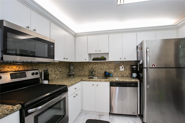 kitchen with dark stone countertops, stainless steel appliances, sink, and white cabinetry