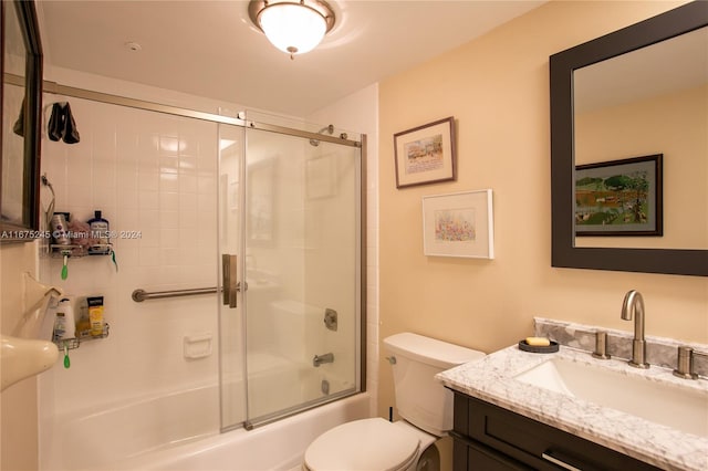 full bathroom featuring vanity, bath / shower combo with glass door, and toilet