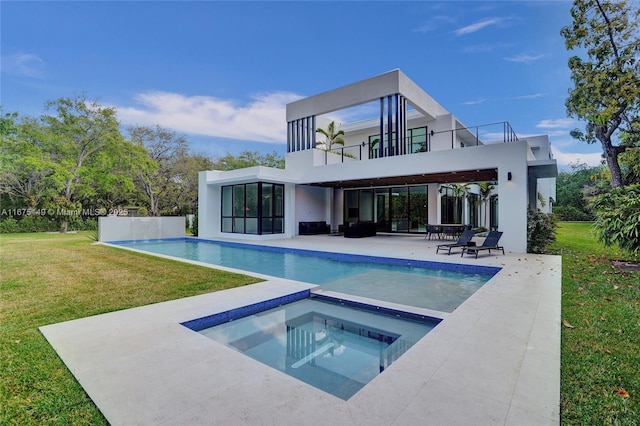 rear view of house with a lawn, stucco siding, a balcony, a patio area, and an in ground hot tub