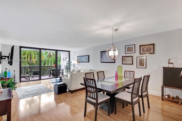 dining area featuring expansive windows, a chandelier, and light hardwood / wood-style flooring