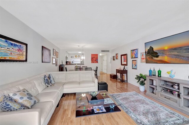 living room featuring an inviting chandelier and light hardwood / wood-style floors