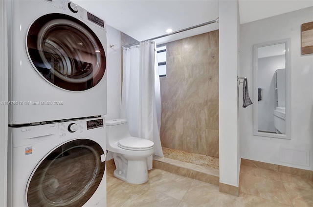 bathroom with stacked washer / dryer, toilet, and curtained shower