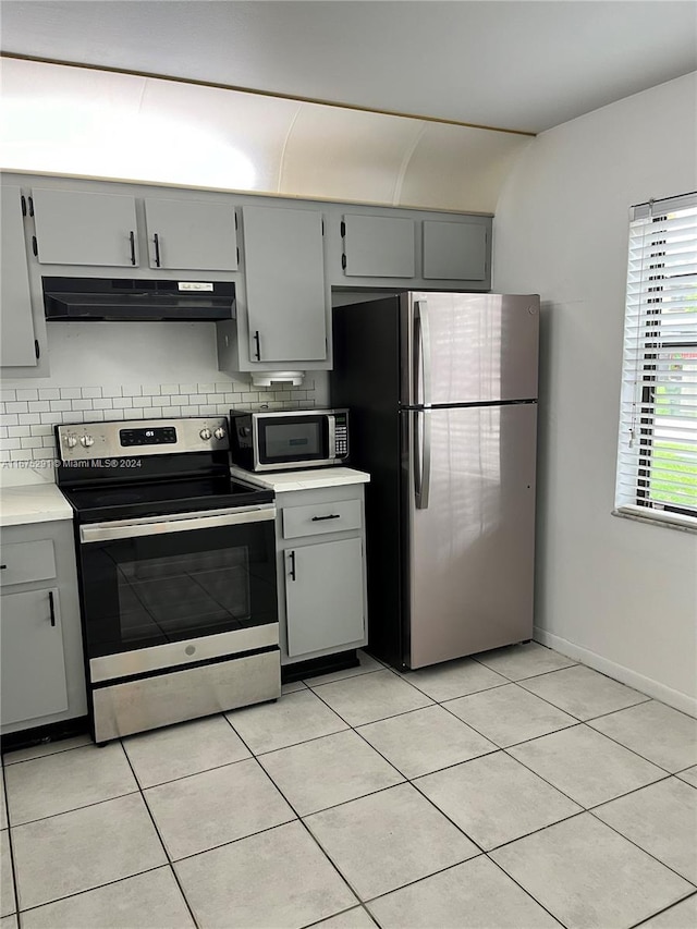kitchen featuring under cabinet range hood, backsplash, appliances with stainless steel finishes, and gray cabinets