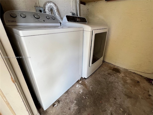 clothes washing area with separate washer and dryer, laundry area, and a textured wall