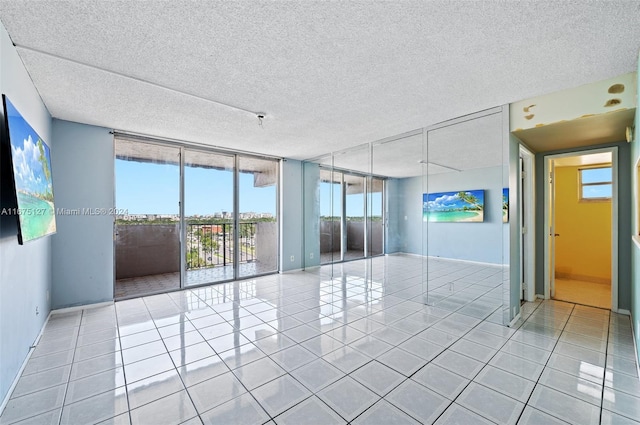 tiled empty room featuring expansive windows and a textured ceiling