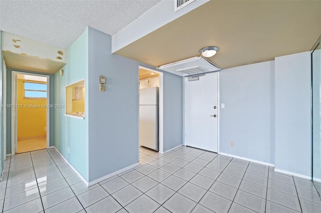 tiled empty room featuring a textured ceiling