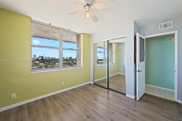 unfurnished bedroom featuring hardwood / wood-style floors, ceiling fan, and a closet