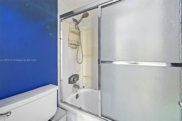 bathroom featuring combined bath / shower with glass door and toilet