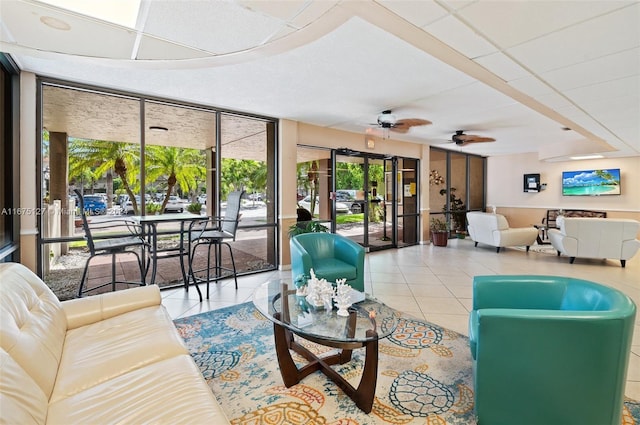 living room with ceiling fan, a drop ceiling, and light tile patterned floors