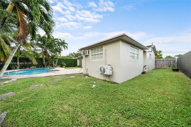 exterior space with a yard, a fenced in pool, and an AC wall unit