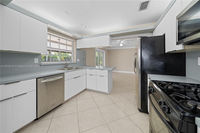 kitchen with kitchen peninsula, stainless steel appliances, sink, light tile patterned floors, and white cabinets