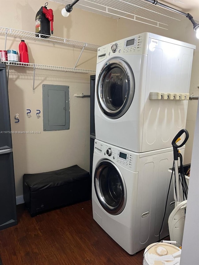 laundry area featuring stacked washing maching and dryer, electric panel, and dark wood-type flooring