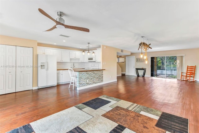 unfurnished living room with dark hardwood / wood-style floors, sink, and ceiling fan with notable chandelier