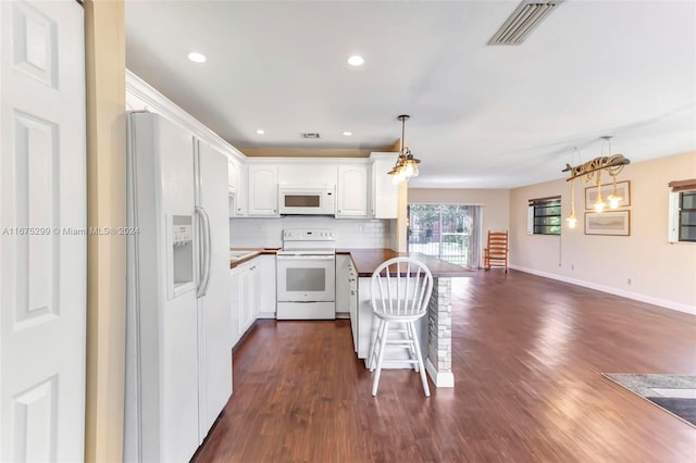 kitchen featuring hanging light fixtures, kitchen peninsula, white cabinets, white appliances, and dark hardwood / wood-style flooring