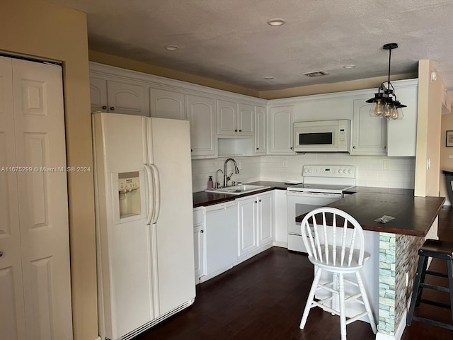 kitchen featuring hanging light fixtures, a breakfast bar, white cabinetry, sink, and white appliances