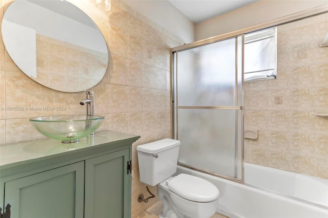 full bathroom with toilet, backsplash, vanity, tile walls, and enclosed tub / shower combo