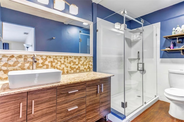 bathroom featuring hardwood / wood-style floors, tile walls, toilet, a shower with shower door, and vanity