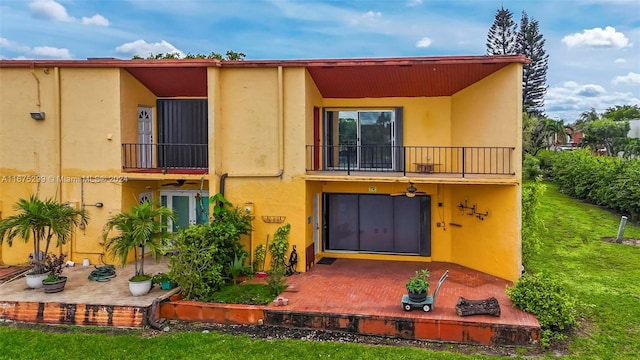 rear view of property with a yard and a balcony