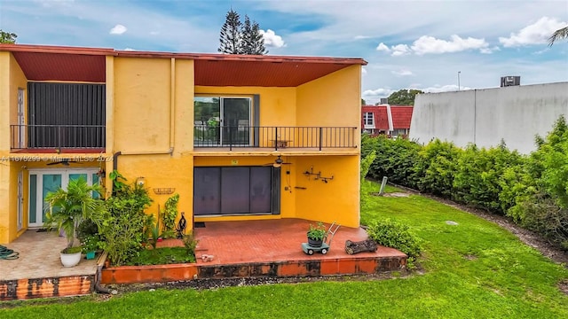 back of property with a patio area, a yard, and a balcony