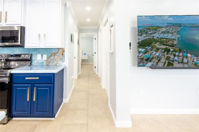 kitchen featuring white cabinets, light tile patterned floors, blue cabinetry, ornamental molding, and stainless steel appliances