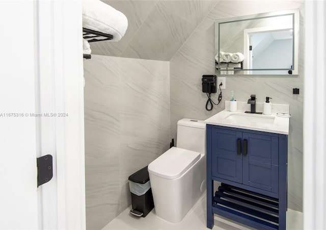 bathroom featuring toilet, vanity, and tile walls