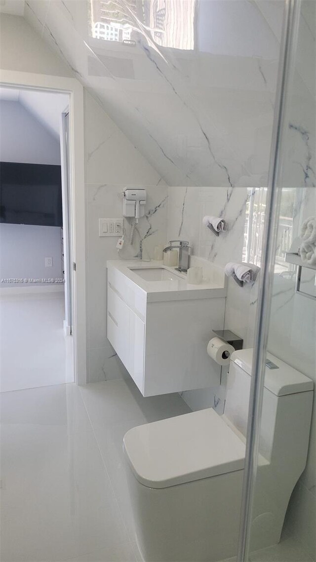 bathroom with tile walls, vanity, lofted ceiling, and toilet