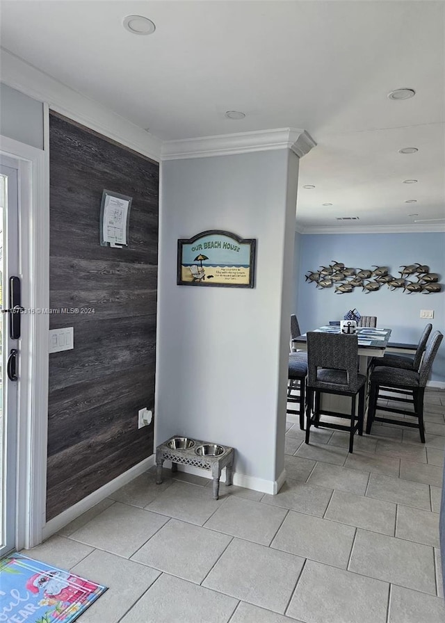 tiled foyer entrance with crown molding and wood walls