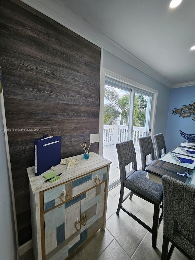 dining room with ornamental molding and wooden walls