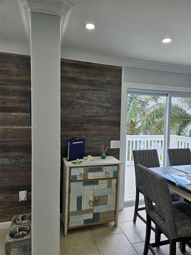 dining space with crown molding, wood walls, and tile patterned floors