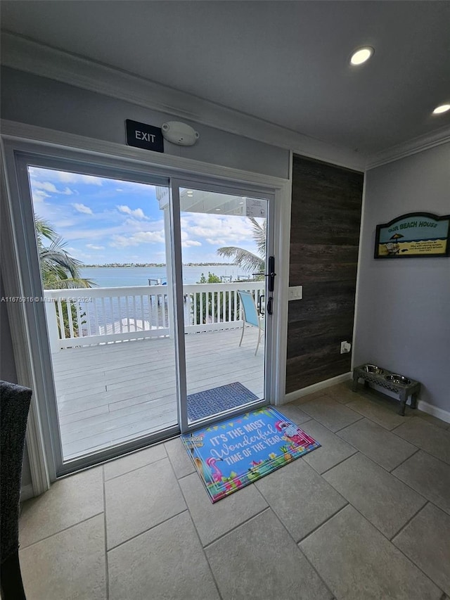 entryway with a water view, wooden walls, ornamental molding, and tile patterned flooring