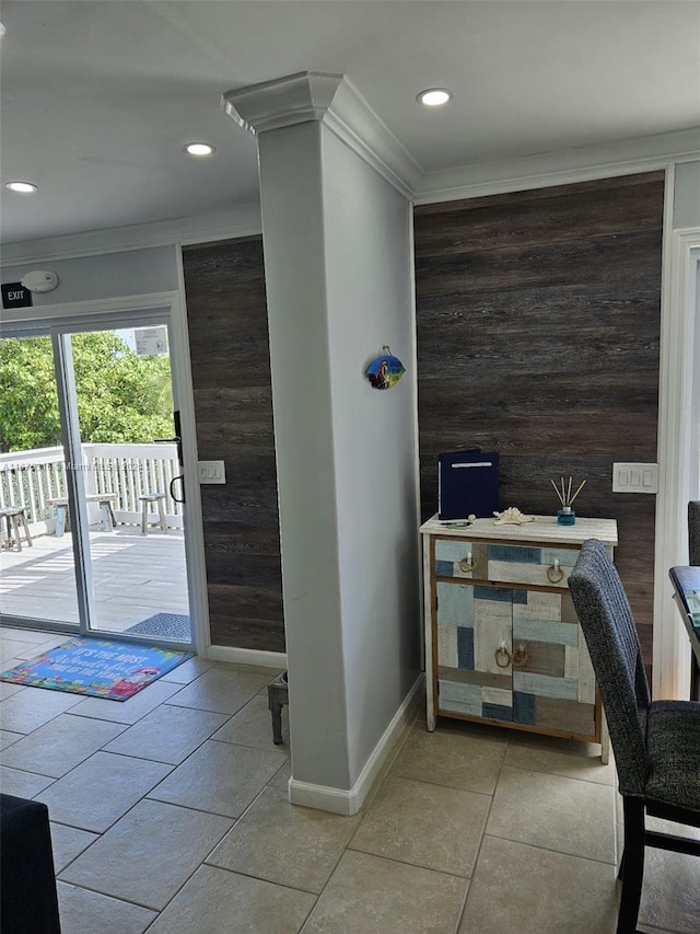 interior space with crown molding, wood walls, and decorative columns