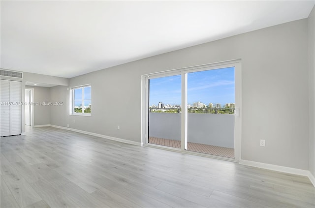 spare room featuring light wood-type flooring, visible vents, and baseboards