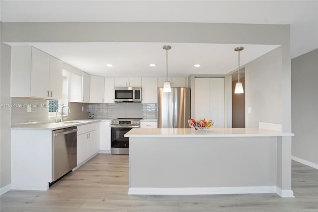 kitchen featuring tasteful backsplash, a sink, light countertops, stainless steel appliances, and light wood-style flooring