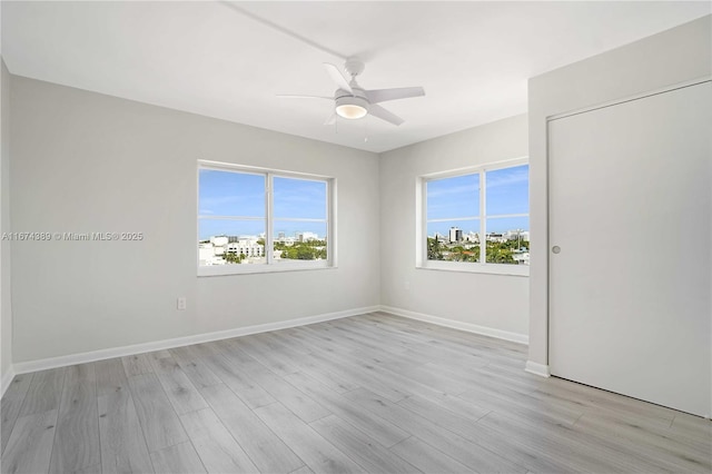 unfurnished room with light wood finished floors, baseboards, and ceiling fan