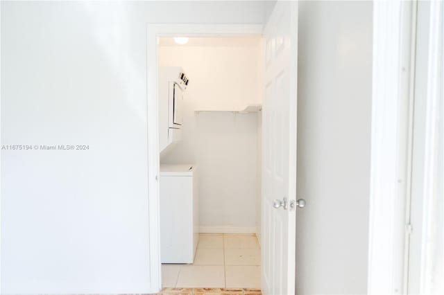 laundry room featuring stacked washer and clothes dryer and light tile patterned floors