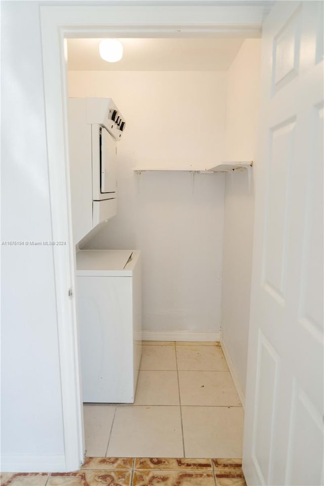 laundry area with stacked washing maching and dryer and light tile patterned floors