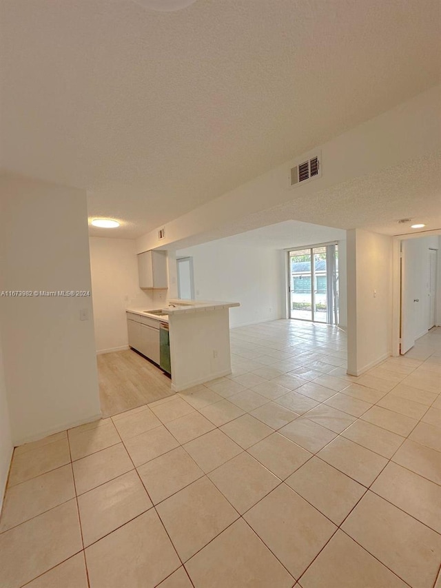 interior space with light tile patterned flooring, kitchen peninsula, and a textured ceiling