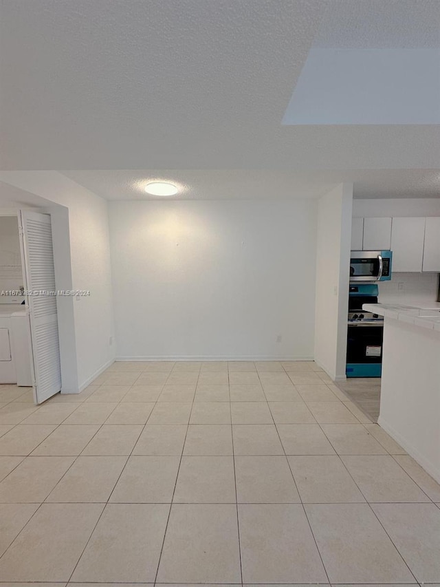 tiled spare room with washer / dryer and a textured ceiling