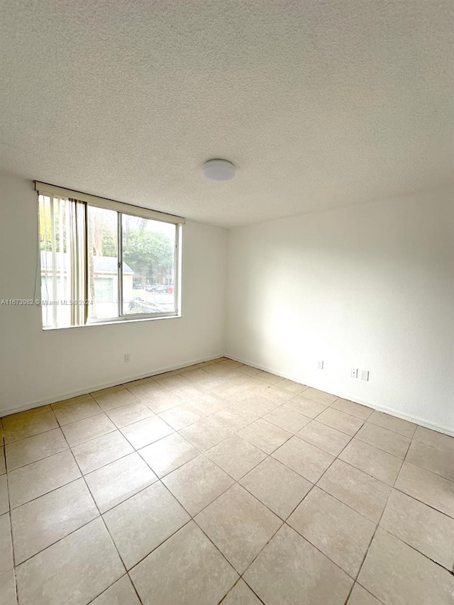 spare room with a textured ceiling and light tile patterned flooring