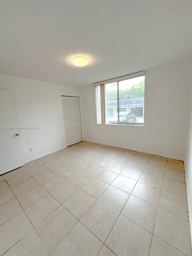 spare room featuring a textured ceiling and light tile patterned floors