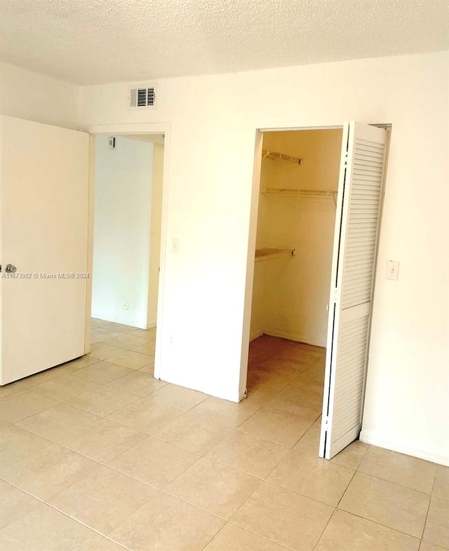 empty room with light tile patterned floors and a textured ceiling