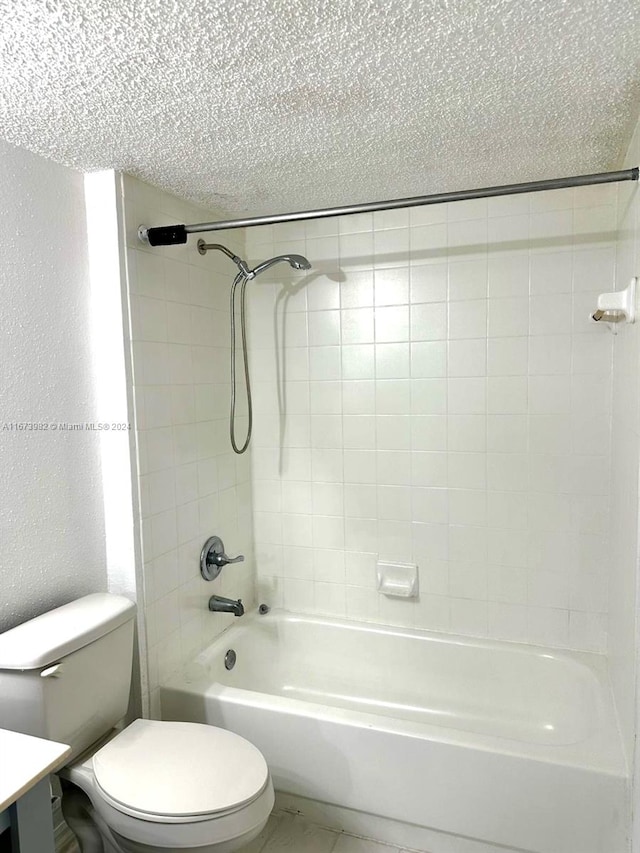 full bathroom featuring a textured ceiling, tiled shower / bath combo, vanity, and toilet