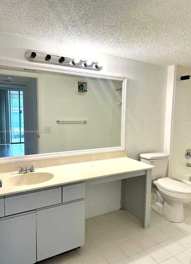 full bathroom featuring tile patterned flooring, toilet, tiled shower / bath, vanity, and a textured ceiling