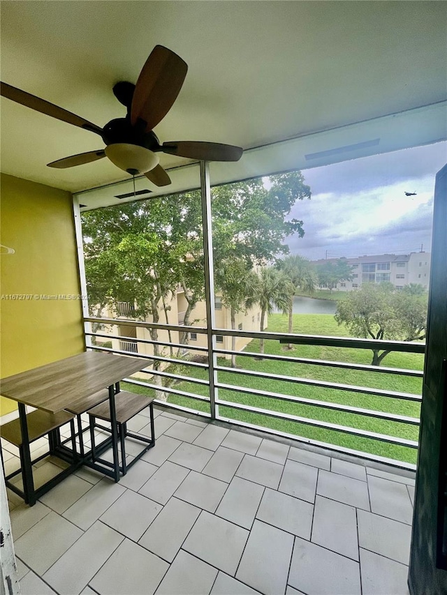 unfurnished sunroom featuring a water view, plenty of natural light, and ceiling fan